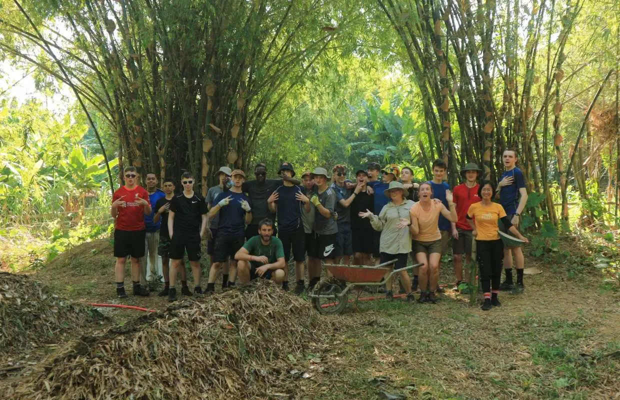 Group participates in Hoi An farm composting workshop amidst bamboo, learning sustainable organic methods.