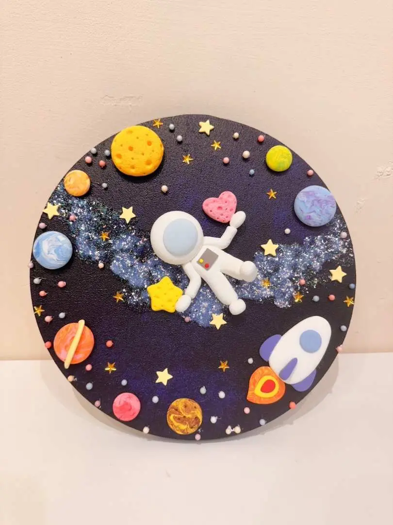 Finished clay painting from Saturn Ring Creative Studio in New Taipei City: a circular space-themed clay artwork delicately depicting an astronaut, planets, stars, and a rocket, full of whimsical wonder and childlike charm.