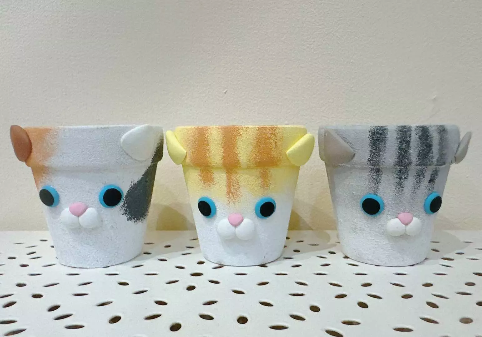 Finished clay handicraft from Saturn Ring Creative Studio: three soft pottery pots with different patterns and cute cat faces, showcasing customized design and the creation of unique artistic works.