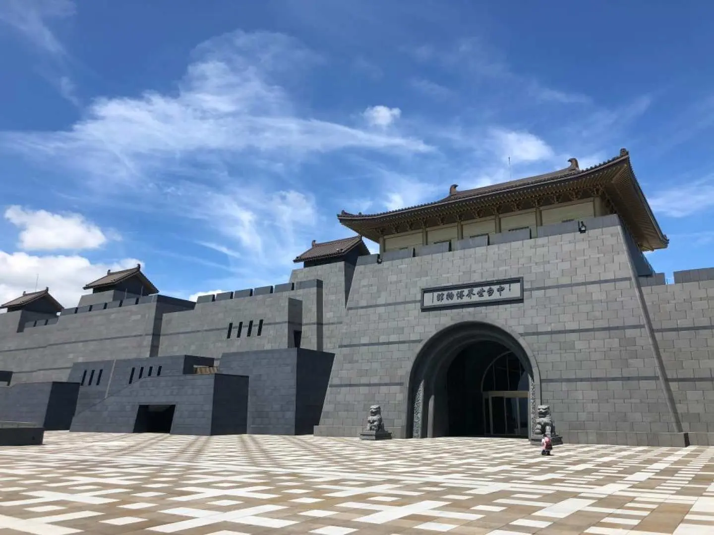 Grand ancient city gate entrance of Chung Tai World Museum in Puli, Nantou, with dark grey stone walls and arched gateways, reflecting the solemn ambiance of Buddhist history and culture.