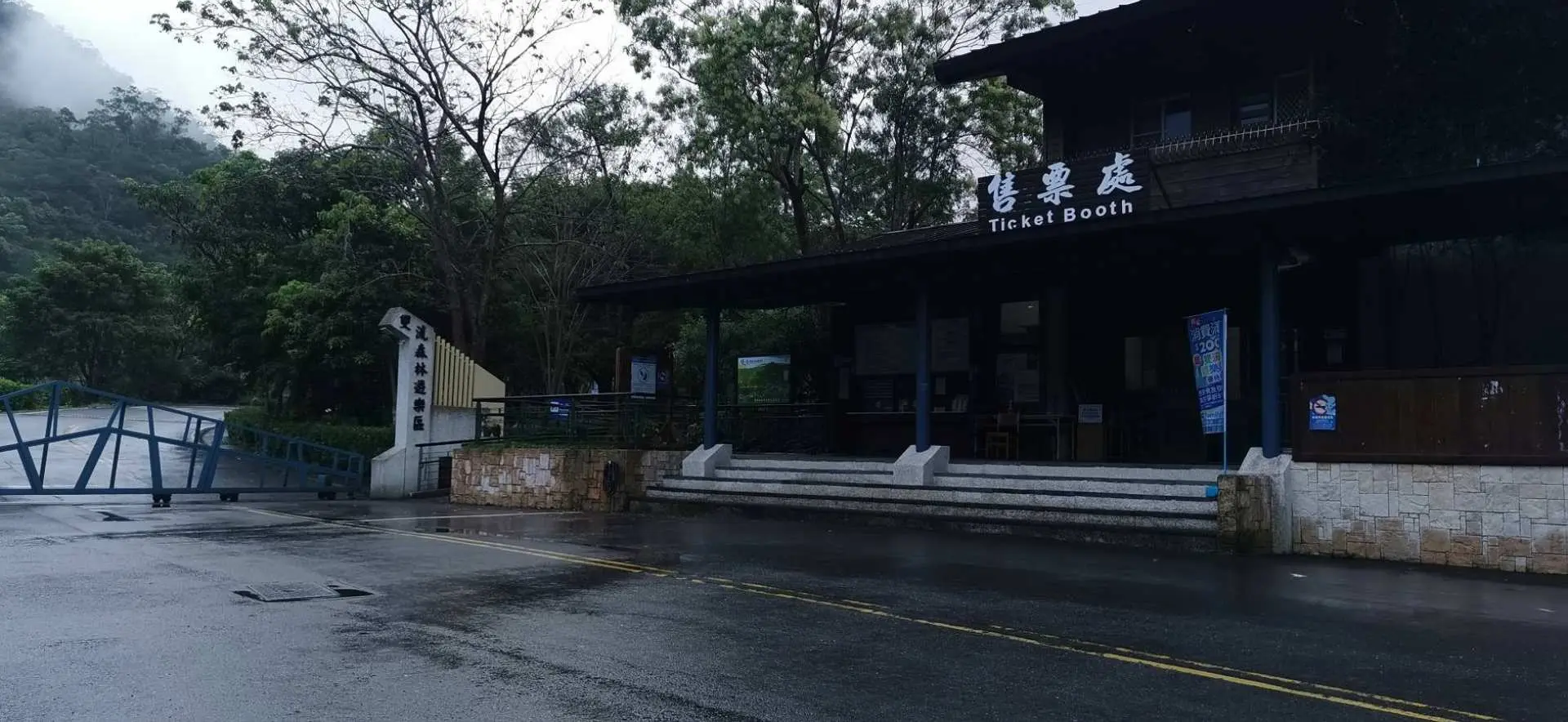 屏東雙流國家森林遊樂區的入口處與售票亭「Ticket Booth」，前方是廣闊的柏油路面，方便遊客停車與購票快速入園。