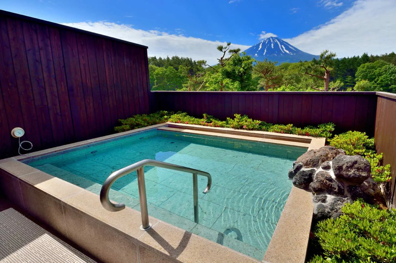 A serene private outdoor bath at Yurari Onsen, surrounded by wooden walls and greenery, offering an exclusive and tranquil view of Mount Fuji.