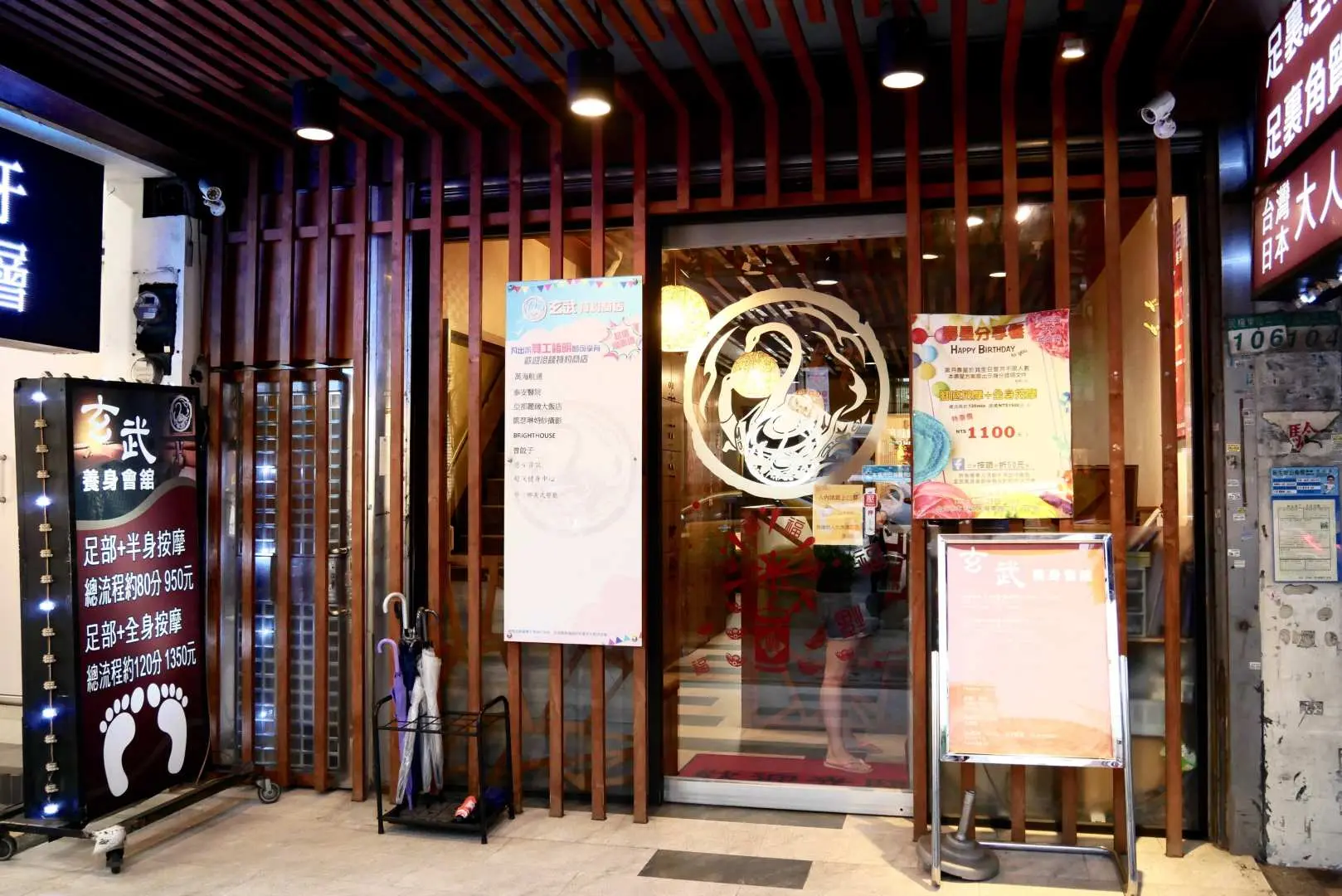 The elegant facade of Taipei's Xuanwu Wellness Center, featuring modern wooden lattice design and signage for foot and full body massage, conveniently located near Xingtian Temple MRT.