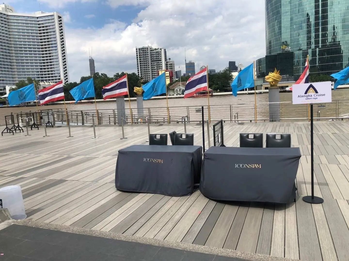 The Alangka Cruise boarding pier in Bangkok, featuring branded registration tables and flags, ready to welcome guests for a luxurious dinner cruise on the Chao Phraya River, ensuring a smooth boarding experience.