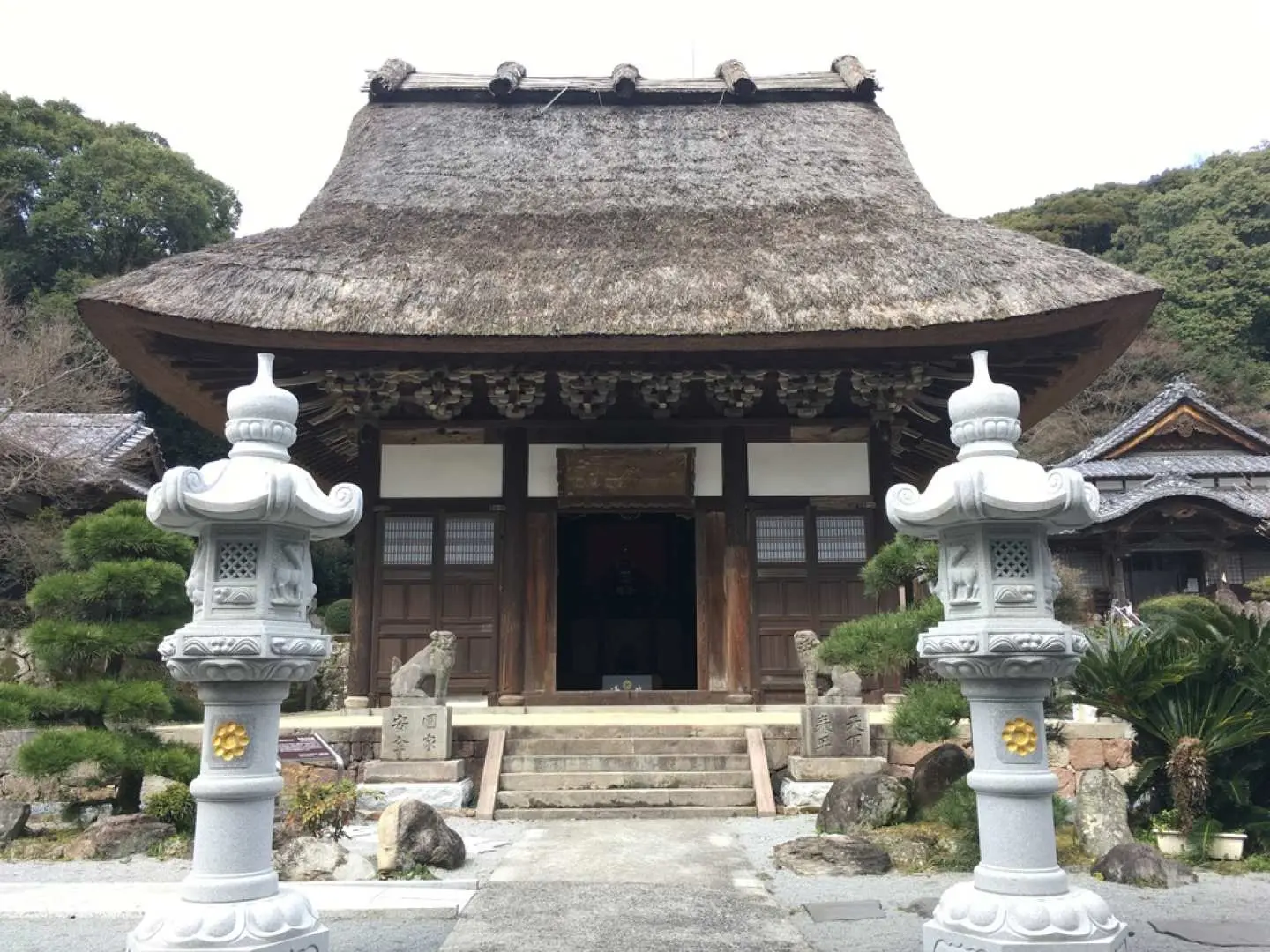 大分国東半島の千福寺にある茅葺き屋根が特徴的な本堂。歴史を感じさせる石灯籠が並び、厳かな雰囲気の中で文化財を見学できます。