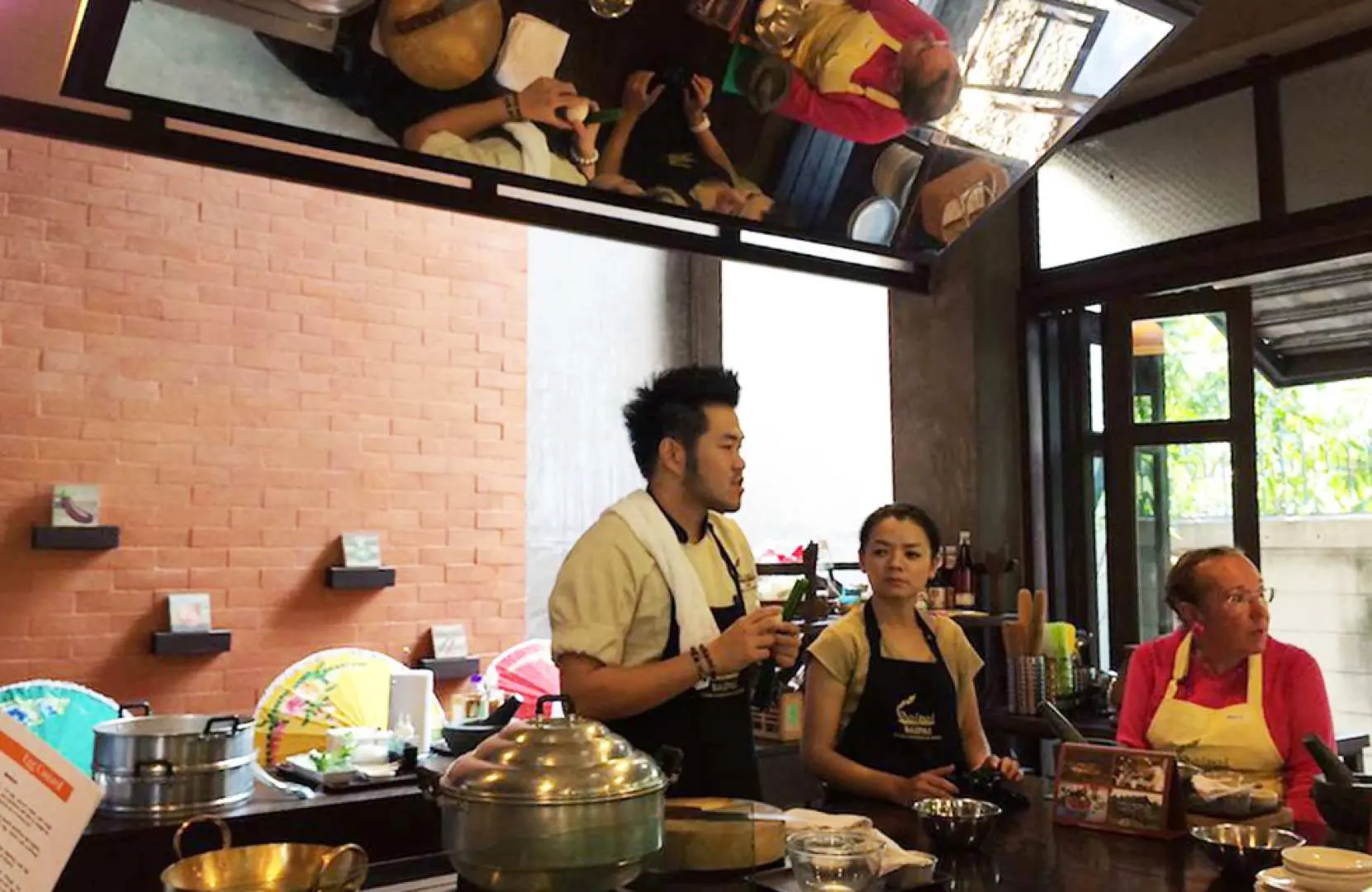 A professional chef instructor at Baipai Thai Cooking School in Bangkok demonstrates cooking techniques to attentive students, sharing expertise in an engaging, hands-on kitchen session.