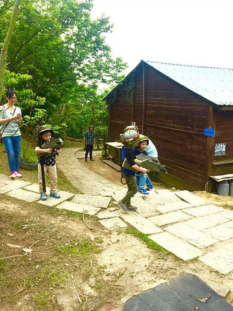 台北鐳戰射擊區戶外場景，親子家庭在綠意盎然的環境中，穿戴裝備準備投入這場刺激又安全的雷射對戰活動。
