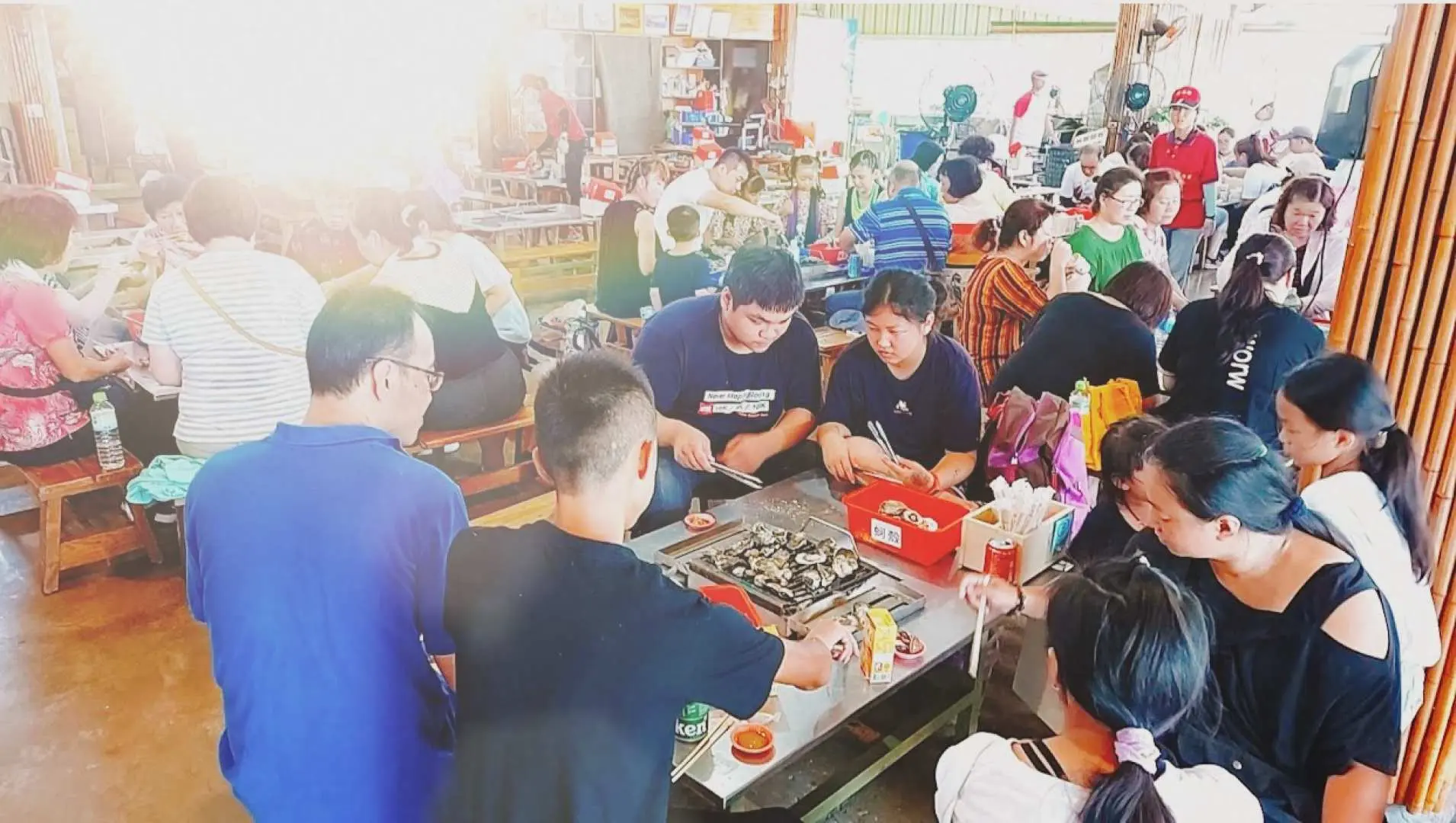 遊客們在台南七股潟湖的餐廳裡，熱絡地享受烤鮮蚵吃到飽，與親友圍爐共享美食，體驗歡樂的用餐時光。