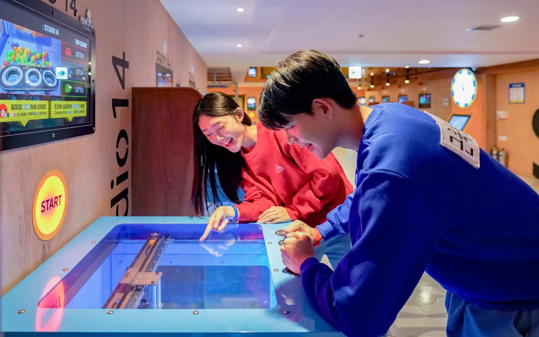Two players collaborate on a touch-interactive board game at Gangneung Running Man Experience Center, solving puzzles together and enjoying the fun of being a Running Man member.