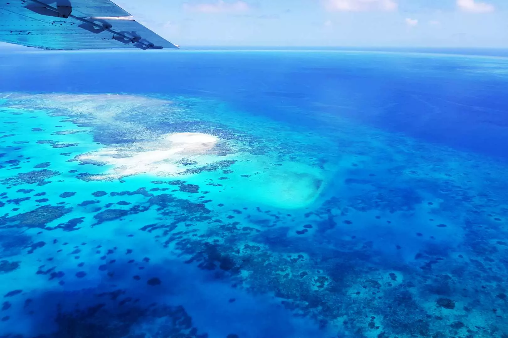 view from plane down at the great barrier reef and crystal blue waters