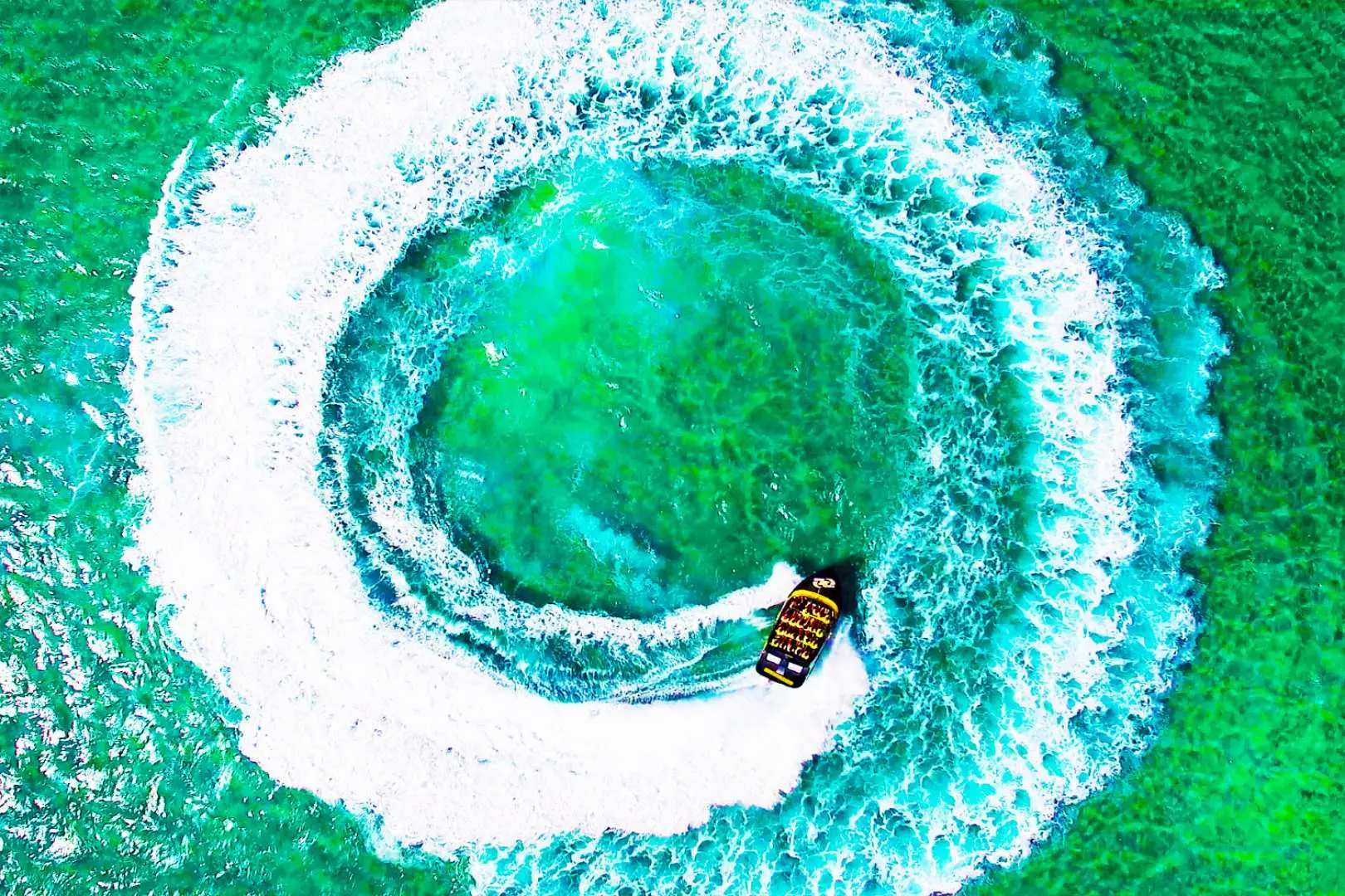 Thrilling Gold Coast jet boat adventure on Broadwater. Aerial view of a 360-degree high-speed spin in emerald water, creating massive white splashes.