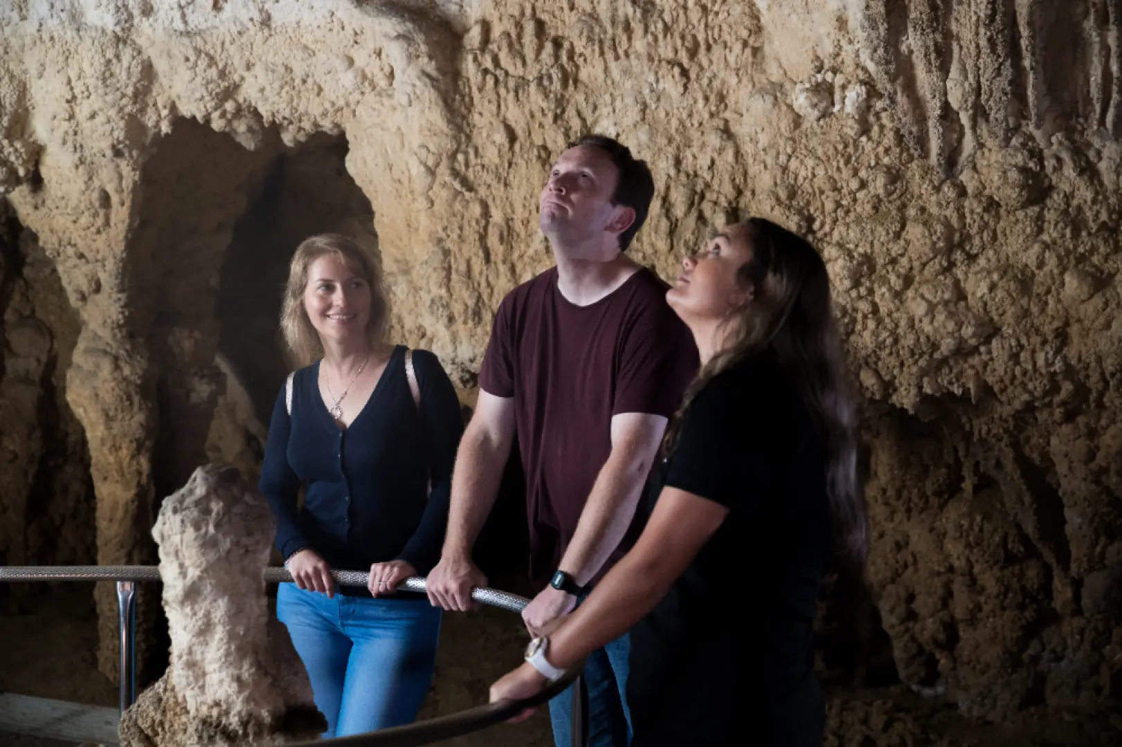 Tourists exploring the intricate rock formations and stunning stalactites inside Waitomo Caves, New Zealand, during a guided tour before the magical glowworm experience.