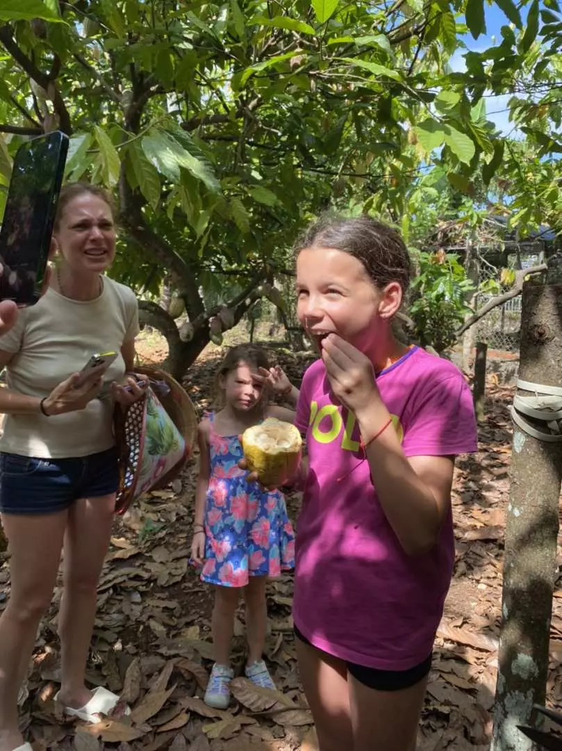 A family enjoying fresh cacao pulp at Binon Cacao Park farm near Ho Chi Minh City, with children excitedly discovering the fruit's natural flavor during their visit.