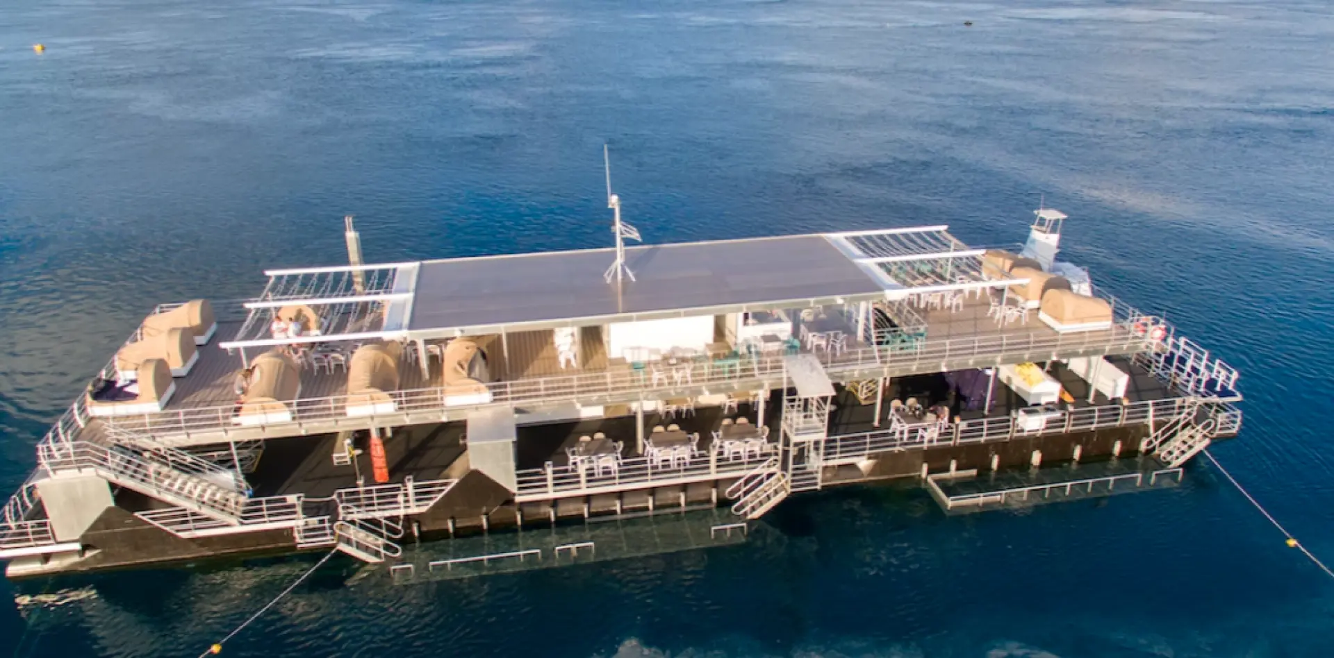 Aerial view of the exclusive Reefworld pontoon at Hardy Reef in the Great Barrier Reef, fully equipped and surrounded by the deep blue ocean.