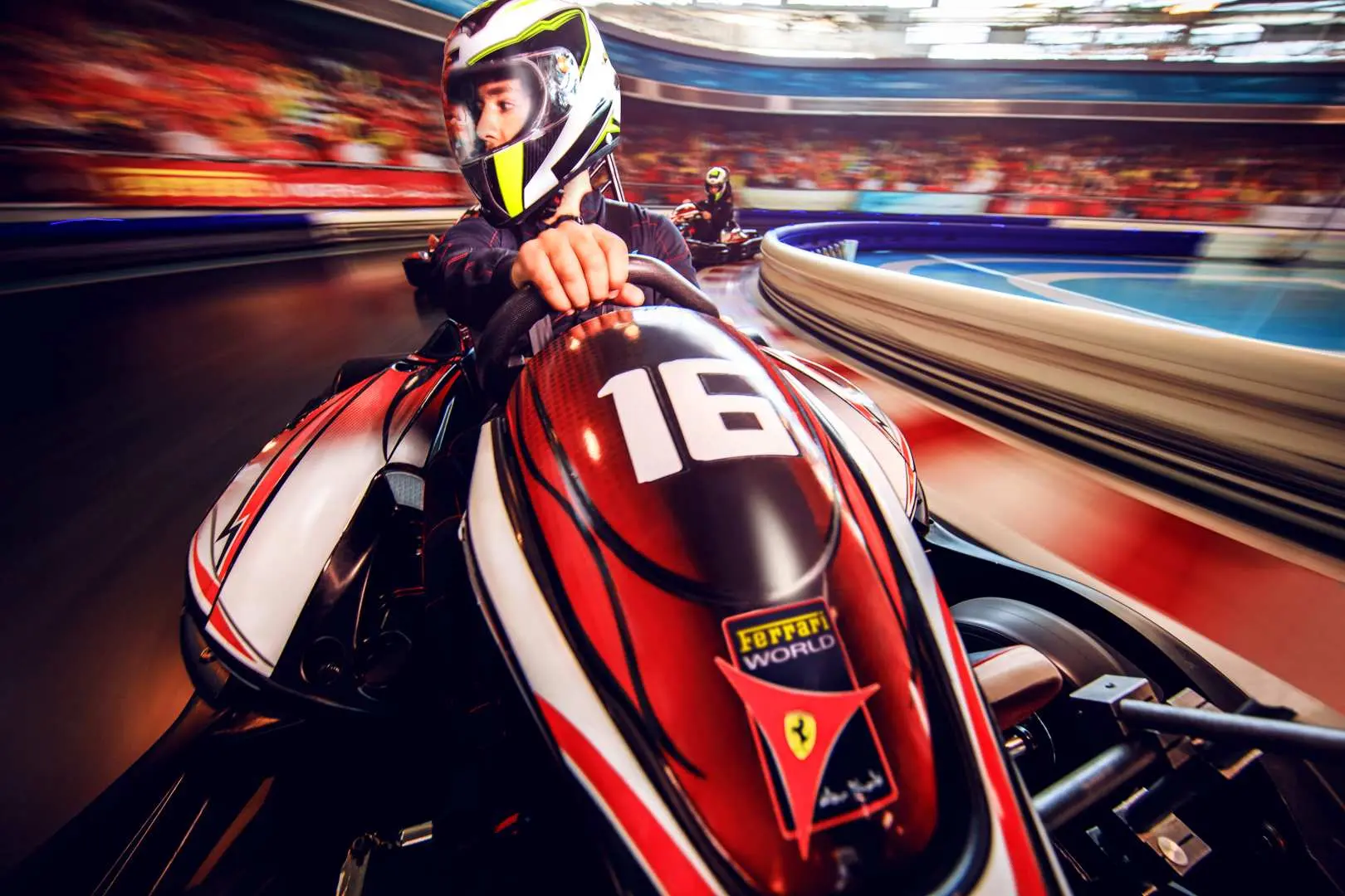A person wearing a helmet and racing suit driving a red go-kart on an indoor track, conveying the excitement of high-speed racing at a Dubai-area attraction.