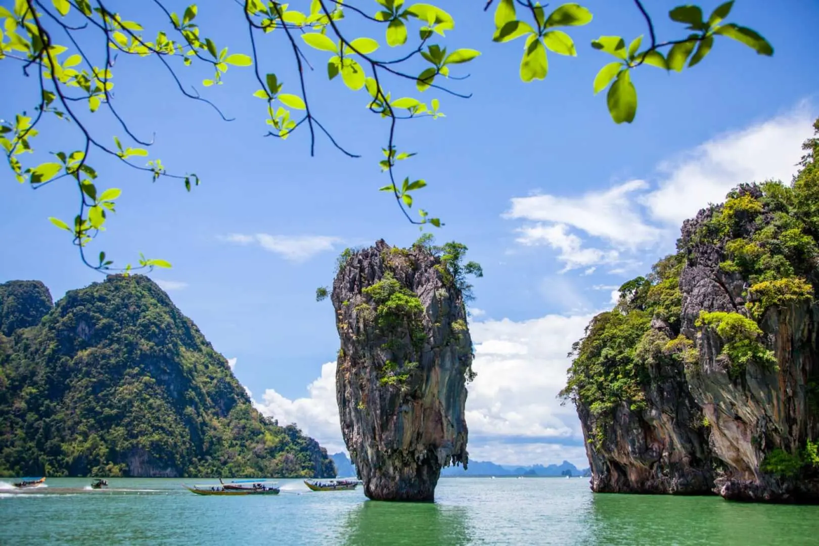 กลุ่มนักท่องเที่ยวพายเรือคายัคในอ่าวพังงา ล่องไปตามน้ำทะเลสีมรกตท่ามกลางภูเขาหินปูนอันตระการตา เพลิดเพลินกับกิจกรรมทางน้ำแบบกลุ่มที่สนุกสนาน