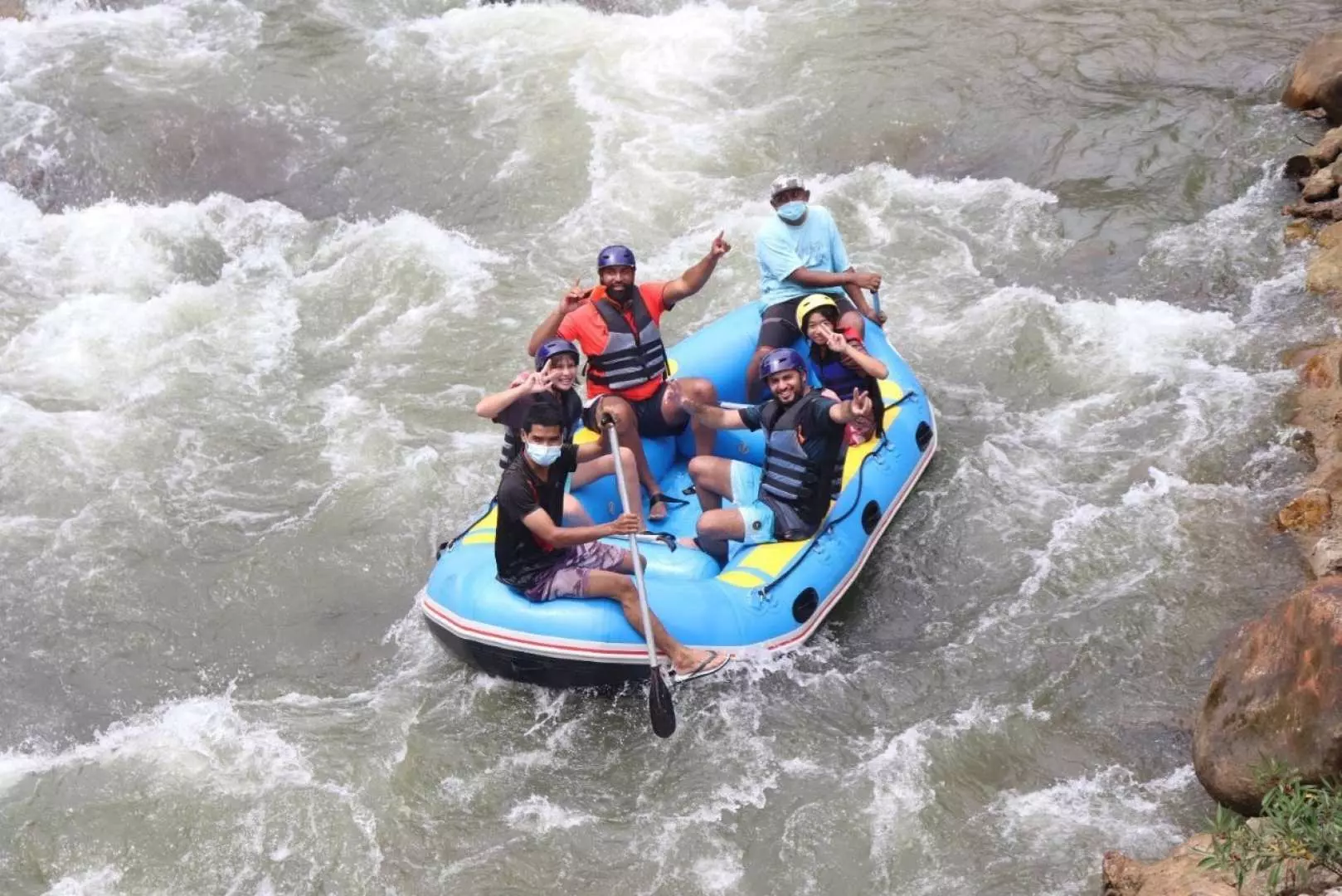 Overhead view of a group in a blue raft, navigating a fast-flowing river during a whitewater rafting tour in Phuket, experiencing teamwork and adventure.