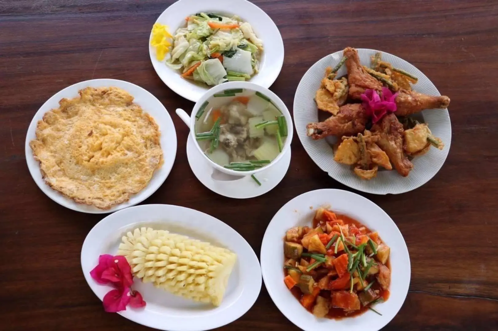 A delicious spread of halal Thai lunch dishes served on a wooden table during the Phuket day tour, featuring stir-fries, soup, and a special fruit.