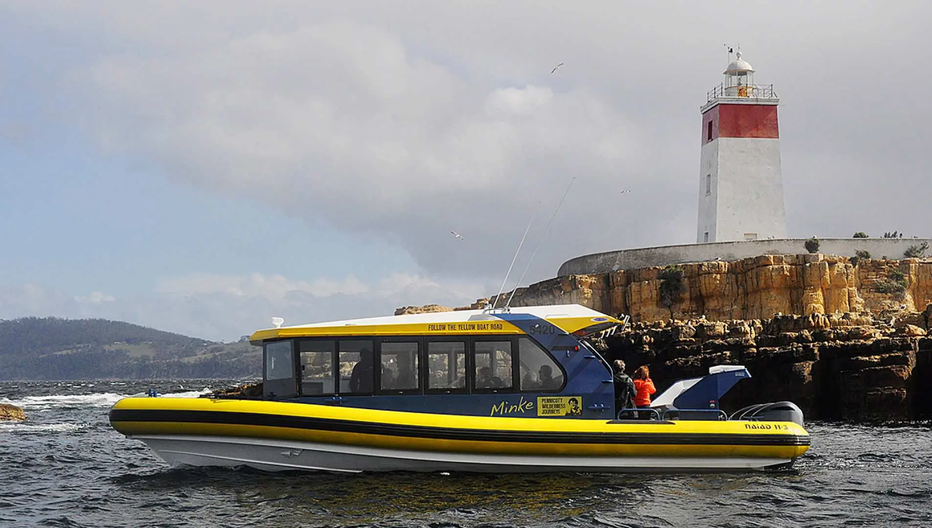 The Hobart Iron Pot cruise boat, with passengers onboard, sails past Australia's oldest lighthouse. Enjoy scenic Tasmanian coastline views and historical sites during this 2.5-hour eco-exploration.