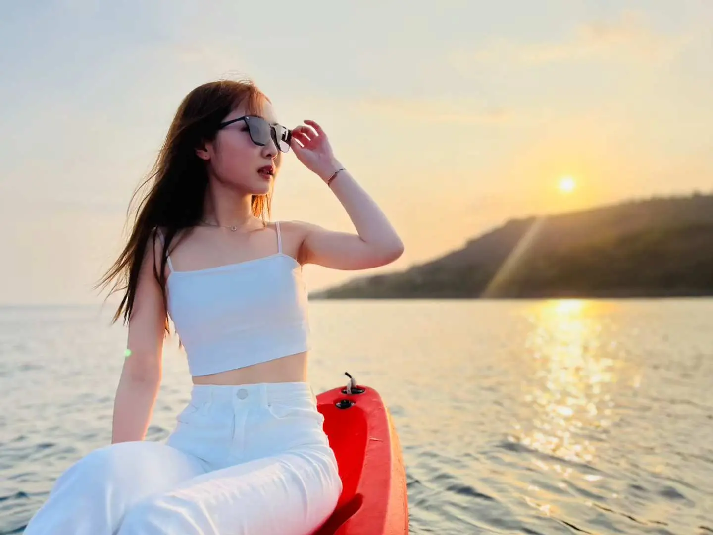 在小琉球珊瑚海上，一位女士坐在獨木舟上欣賞迷人日落夕陽美景，享受寧靜與浪漫的水上體驗。