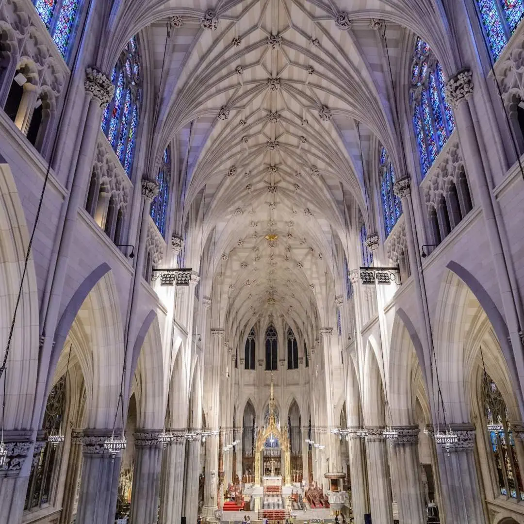 The majestic and ornate interior nave of St. Patrick's Cathedral, showcasing towering vaulted ceilings and intricate Gothic architectural details, inviting visitors to delve into its history and aesthetics with an audio tour.