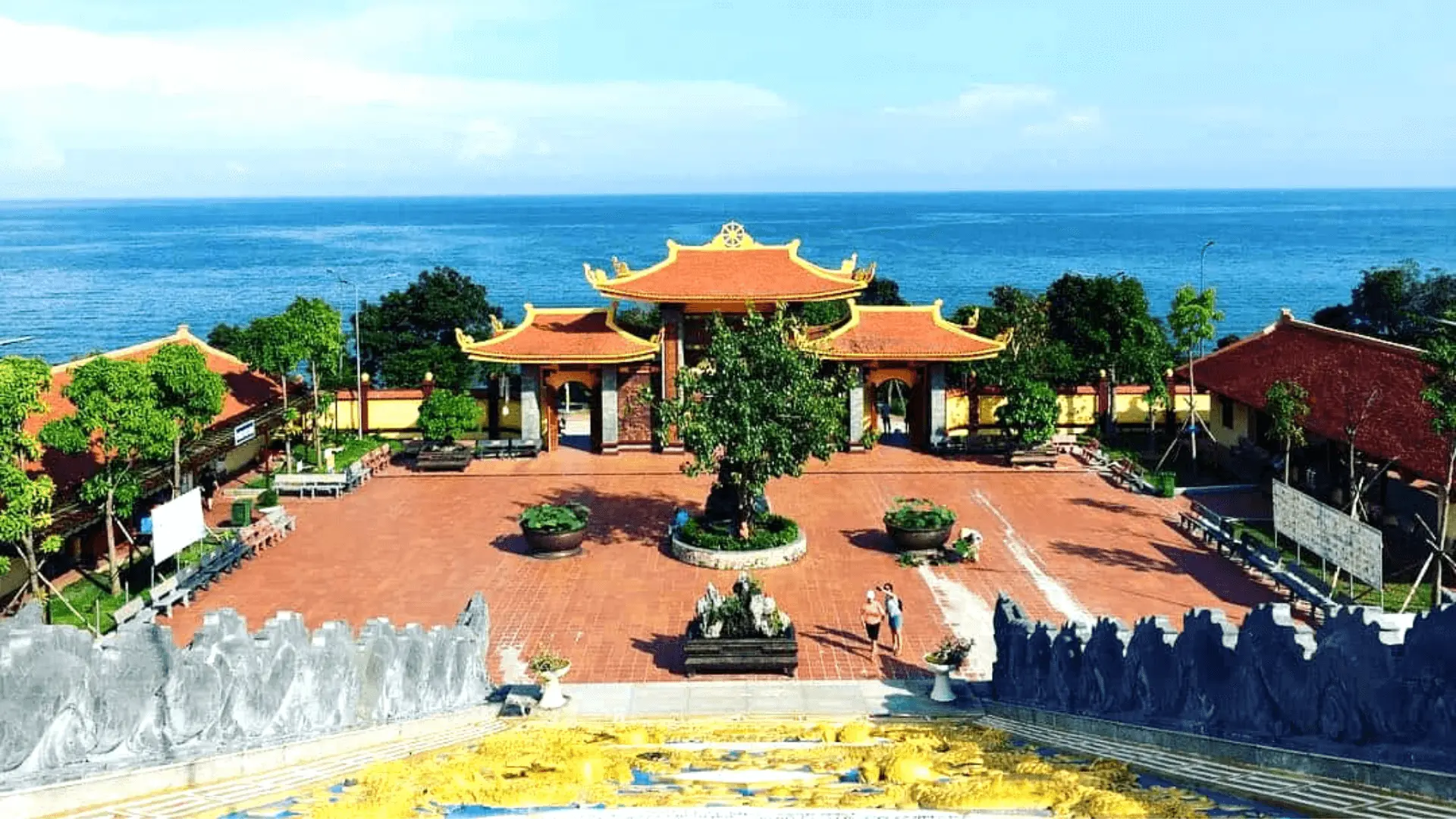 参观 Ho Quoc 塔，见证蓝天和 Bai Dam 海滩外的海水构成寺庙门檐，后面是绿色的山丘。