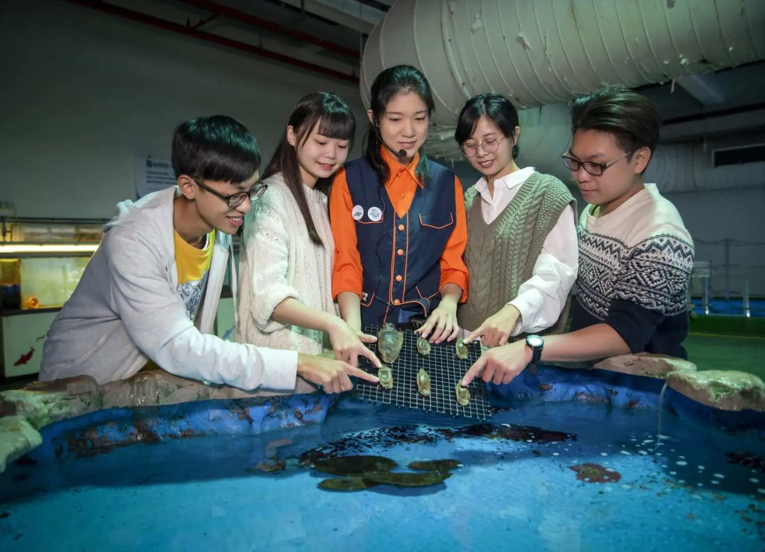 Participants of Pingtung NMMBA's 'Fish with You' experience, guided by an aquarist behind-the-scenes, observing marine life up close.