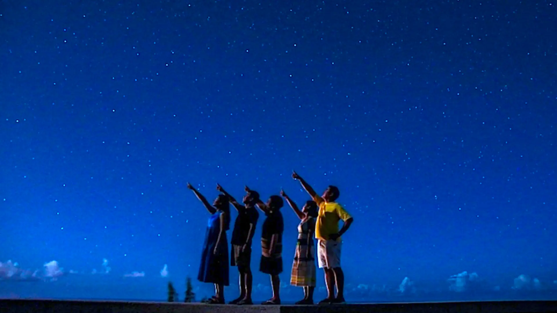 Nhóm bạn tham gia tour ngắm sao ở Guam đang chỉ lên bầu trời đầy sao, cùng nhau tận hưởng cảnh đêm lãng mạn.