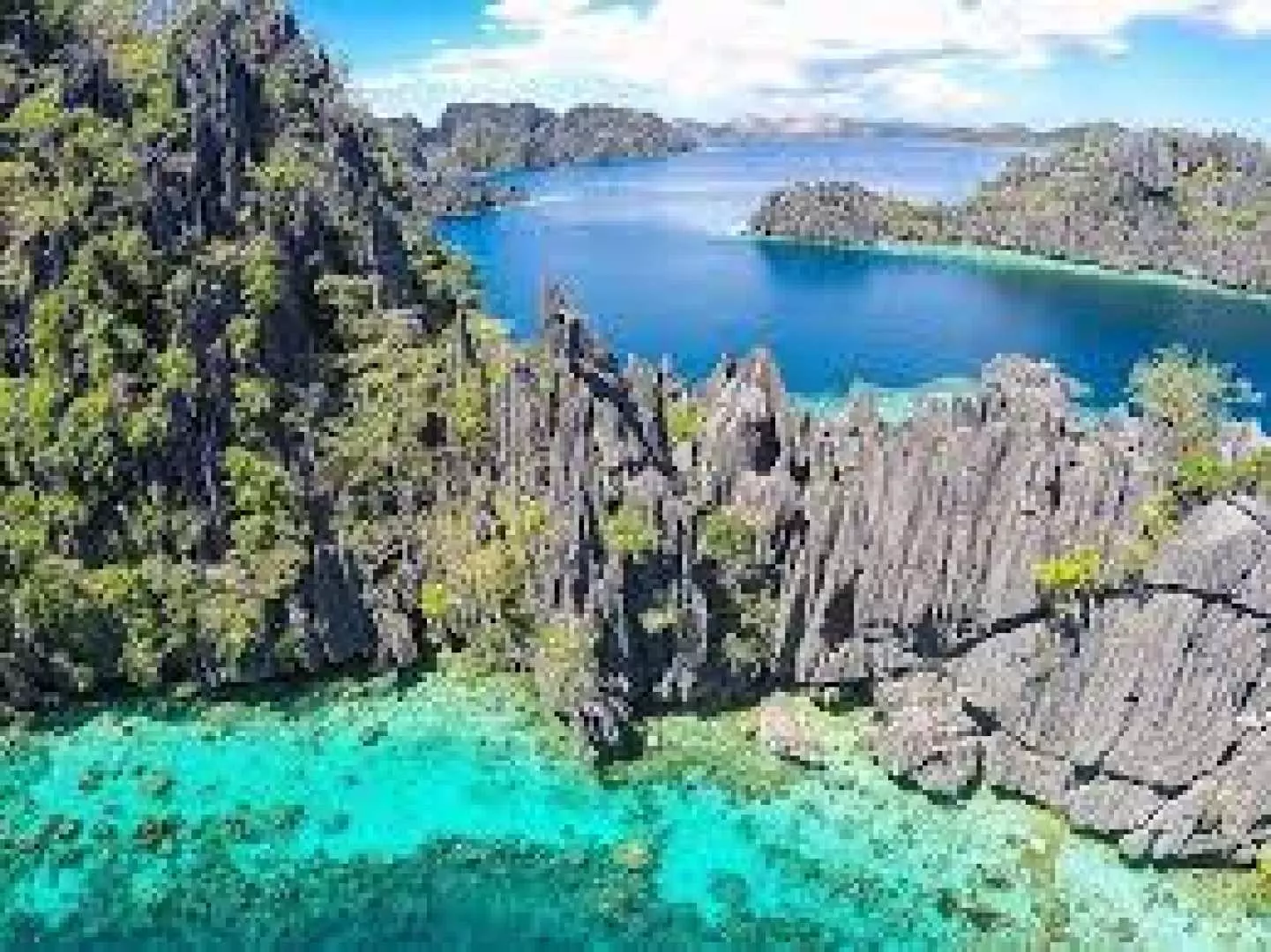 Breathtaking aerial view of Coron's dramatic limestone islands rising from the vibrant turquoise and deep blue waters, showcasing the diverse landscapes of this Philippine paradise.