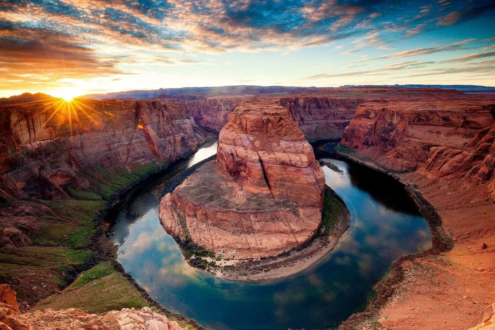 Iconic Horseshoe Bend at sunset, showcasing the vibrant Colorado River curving around the rock formation, bathed in the golden hues of the Arizona evening sky.