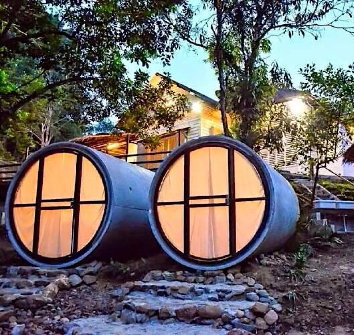 Enchanting night view of the illuminated concrete pipe capsule rooms at Time Capsule Retreat Sungai Lembing, exuding a warm and inviting glow amidst the serene Pahang forest.