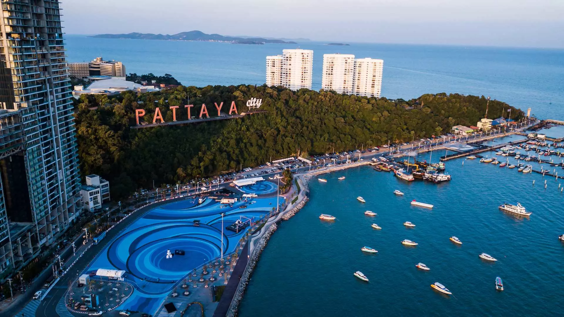 Panoramic aerial view of Pattaya City, Chonburi, Thailand, with 'PATTAYA City' landmark, coastline, marina, and modern buildings, showcasing a vibrant destination for airport transfer travelers.