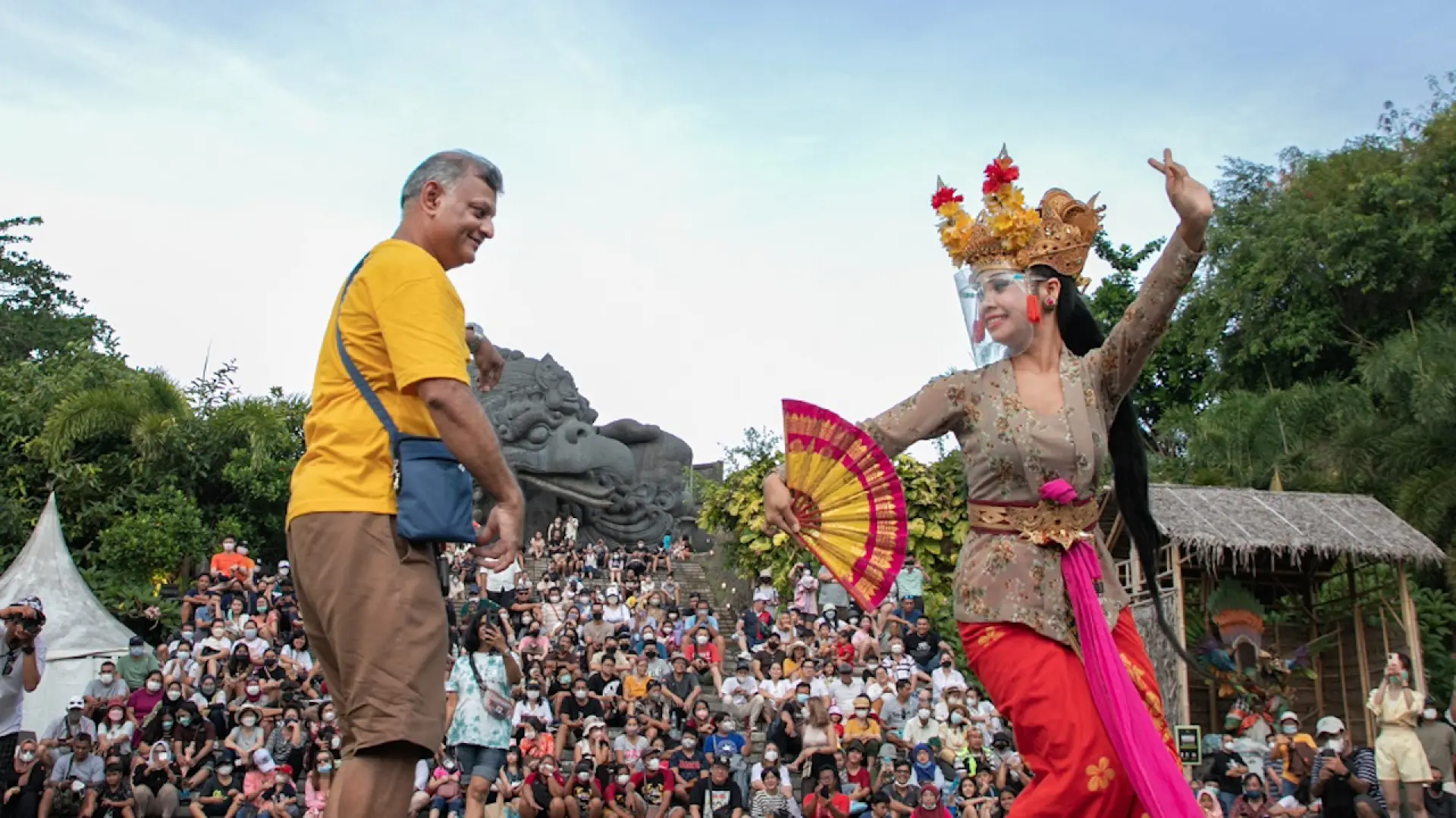 การแสดงวัฒนธรรมบาหลีที่เปี่ยมชีวิตชีวา ณ สวนวัฒนธรรม GWK โดยมีนักเต้นรำพื้นเมืองกำลังมีปฏิสัมพันธ์กับผู้ชม พร้อมรูปปั้นครุฑอันสง่างามปรากฏให้เห็นอยู่เบื้องหลัง