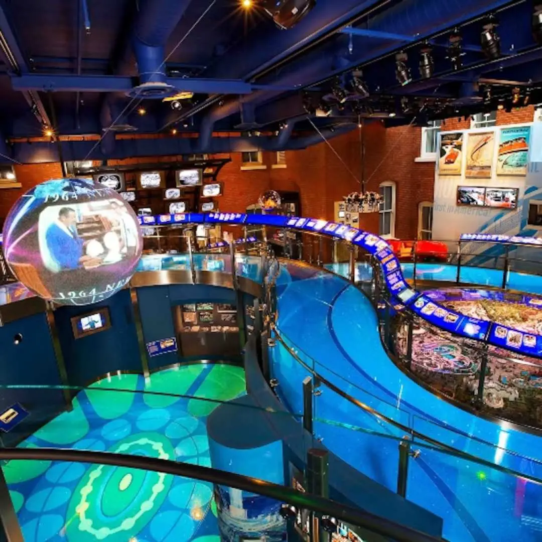 A modern, interactive exhibit at The Walt Disney Family Museum in San Francisco, featuring a blue curved pathway and large circular screens, showcasing the magical journey of Disney film production and creative development.