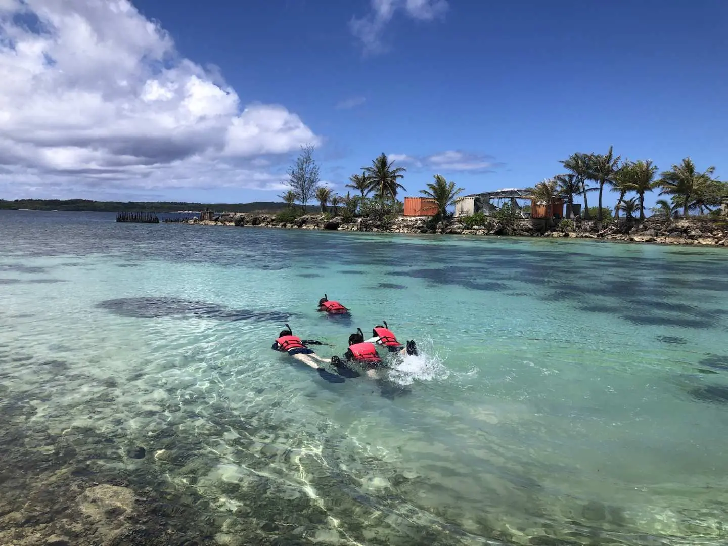 幾位遊客在關島海洋公園清澈碧綠的海水中享受浮潛樂趣，探索水下世界，體驗大自然之美。
