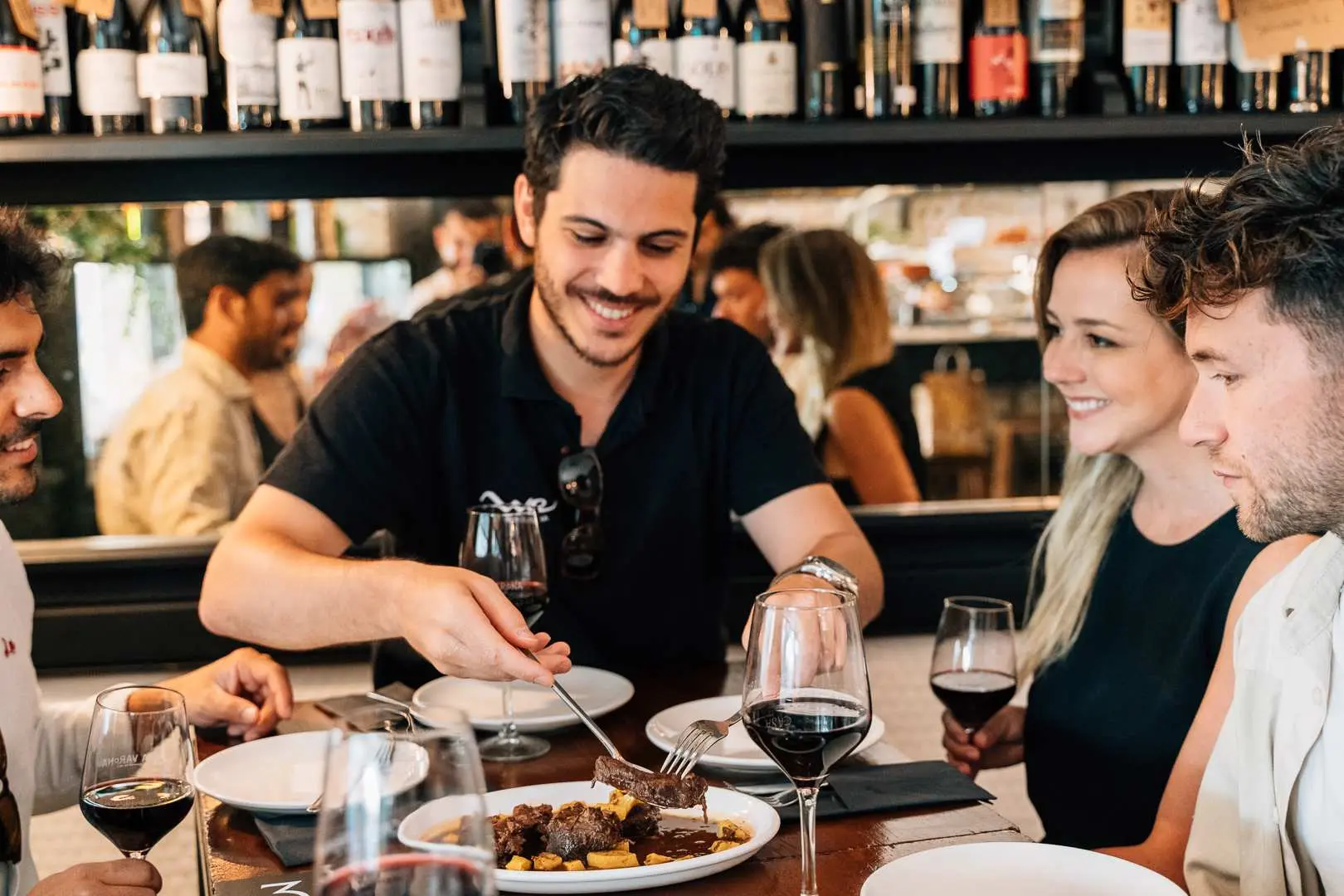 Madrid food tour: Friends enjoying delicious Spanish cuisine and wine at a local restaurant, experiencing authentic culinary culture and lively atmosphere.