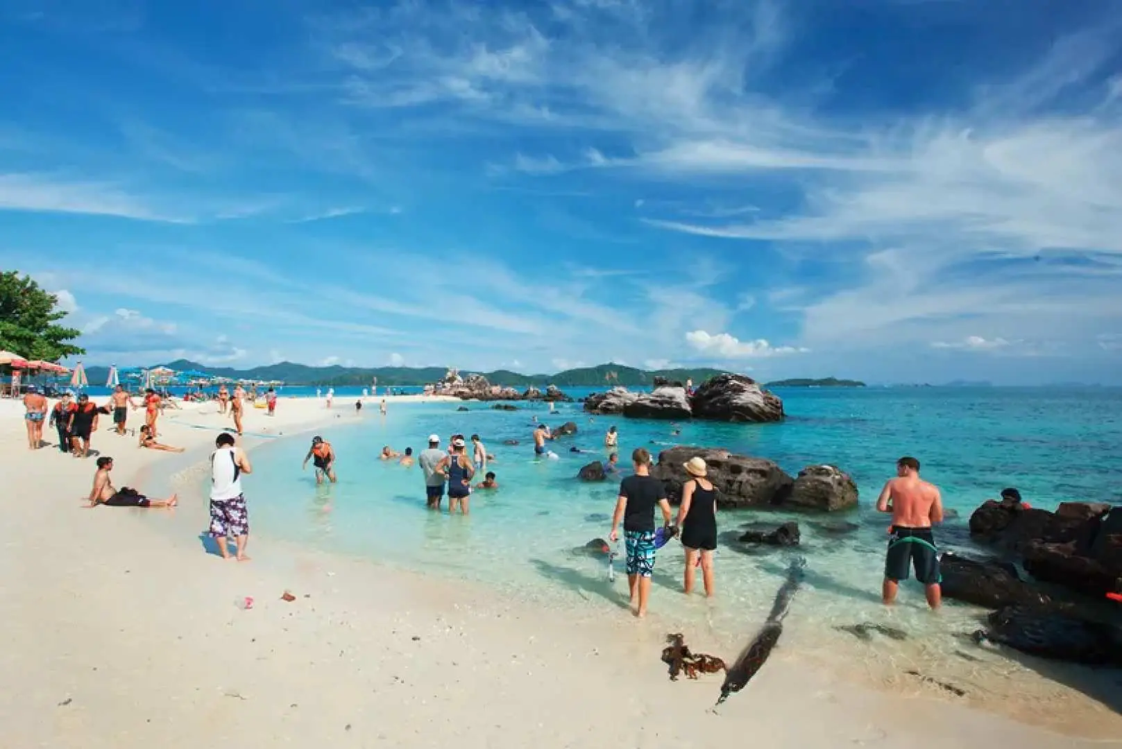 Tourists enjoy the pristine white sands and clear turquoise waters of Khai or Phi Phi Islands, Phuket, swimming and sunbathing, reflecting a relaxed tropical island getaway.