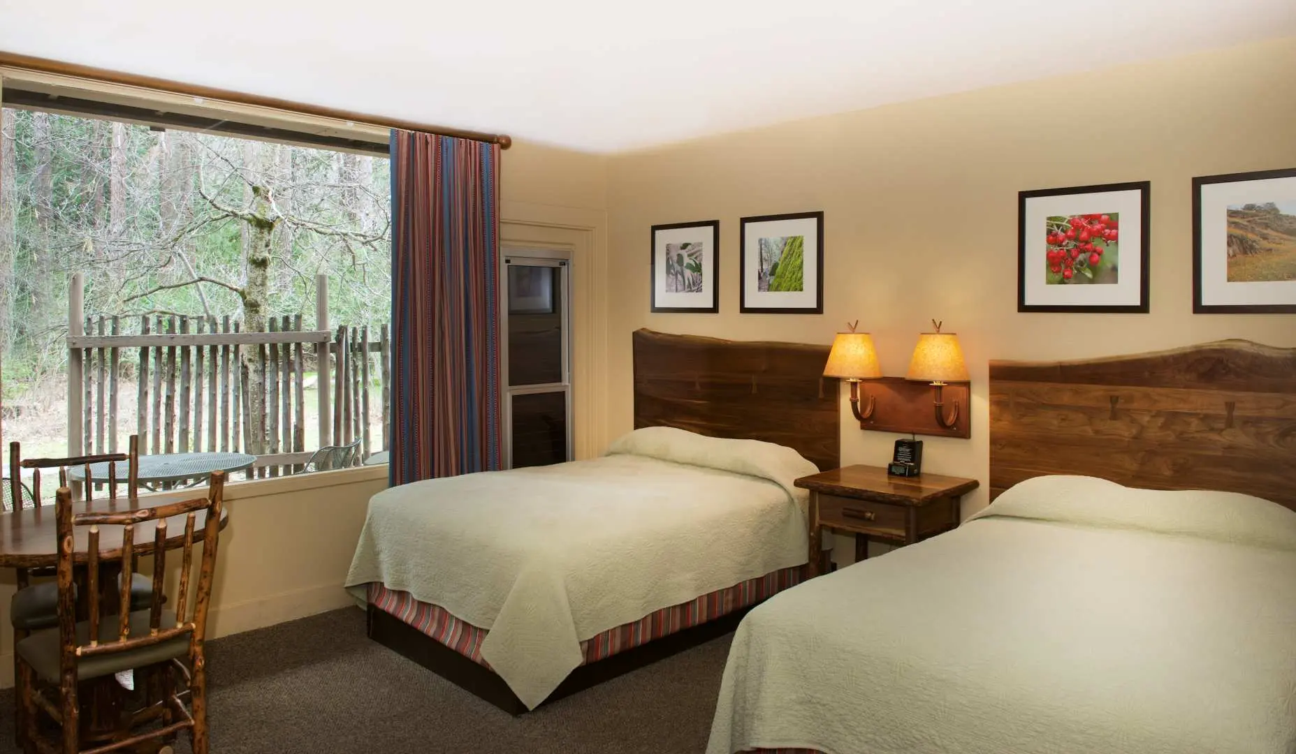 A comfortable hotel room within Yosemite National Park, featuring two double beds and views of lush trees outside the window, offering cozy accommodation.