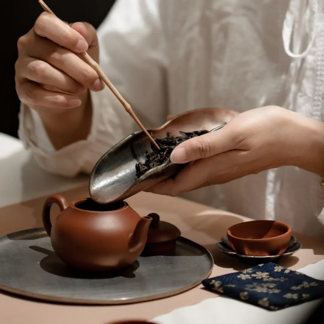 台北大稻埕親手泡茶體驗，近距離拍攝學員以茶匙將台灣茶葉裝入陶壺，感受台式泡茶的儀式感與細節。
