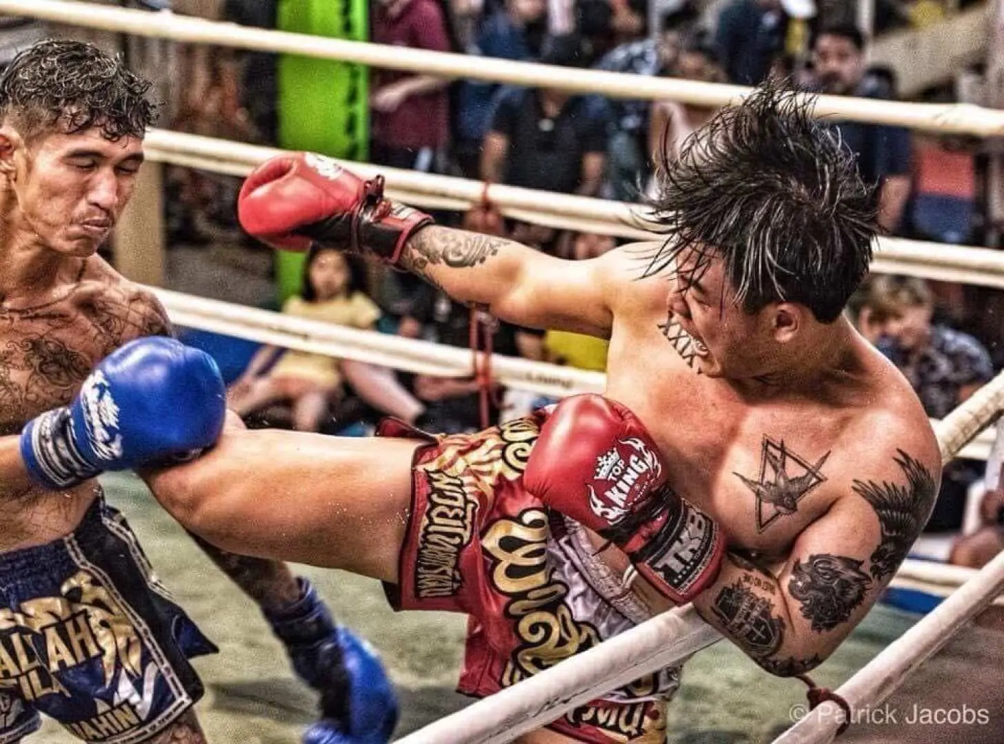 Close-up action shot of a Muay Thai fight at Hua Hin's Thai Boxing Garden, featuring a boxer delivering a precise high kick while the opponent prepares to defend, showcasing raw power and agility.