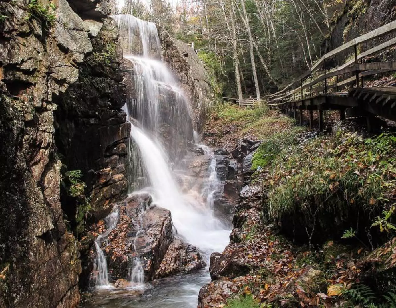 墾丁七孔瀑布的壯麗自然景色，多層瀑布沿著岩壁傾瀉而下，旁有木棧道，展現溯溪體驗的原始環境。