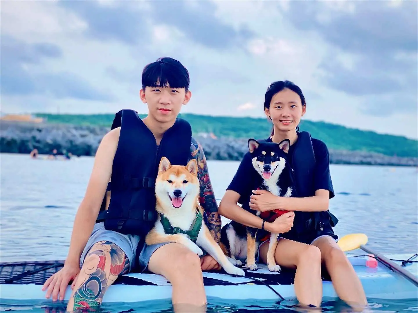 小琉球SUP宠物友善体验，情侣带着两只可爱柴犬坐在立桨板上，一同享受海上活动的乐趣与温馨。