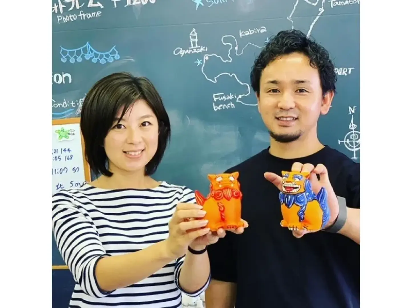 Cặp đôi hạnh phúc ở Okinawa tự hào khoe những bức tượng thần hộ mệnh Shisa màu cam và xanh sống động do chính họ vẽ, sau trải nghiệm tô màu thú vị tại xưởng thủ công.