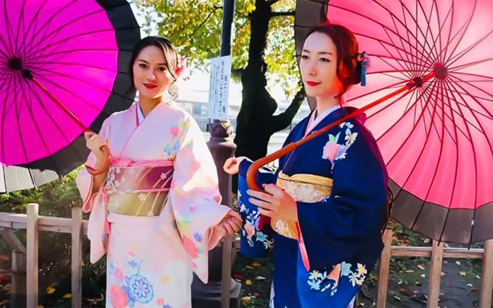着物を着た女性2人が鮮やかなピンクの和傘を手に浅草の街角で旅の喜びを表現し、着物体験を満喫。