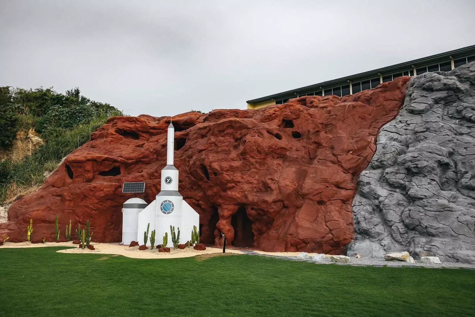 LOF LAND's unique Mars-like landscape in Thailand, with a white rocket structure and cacti against contrasting red and grey rocky terrain, evoking an alien planet.