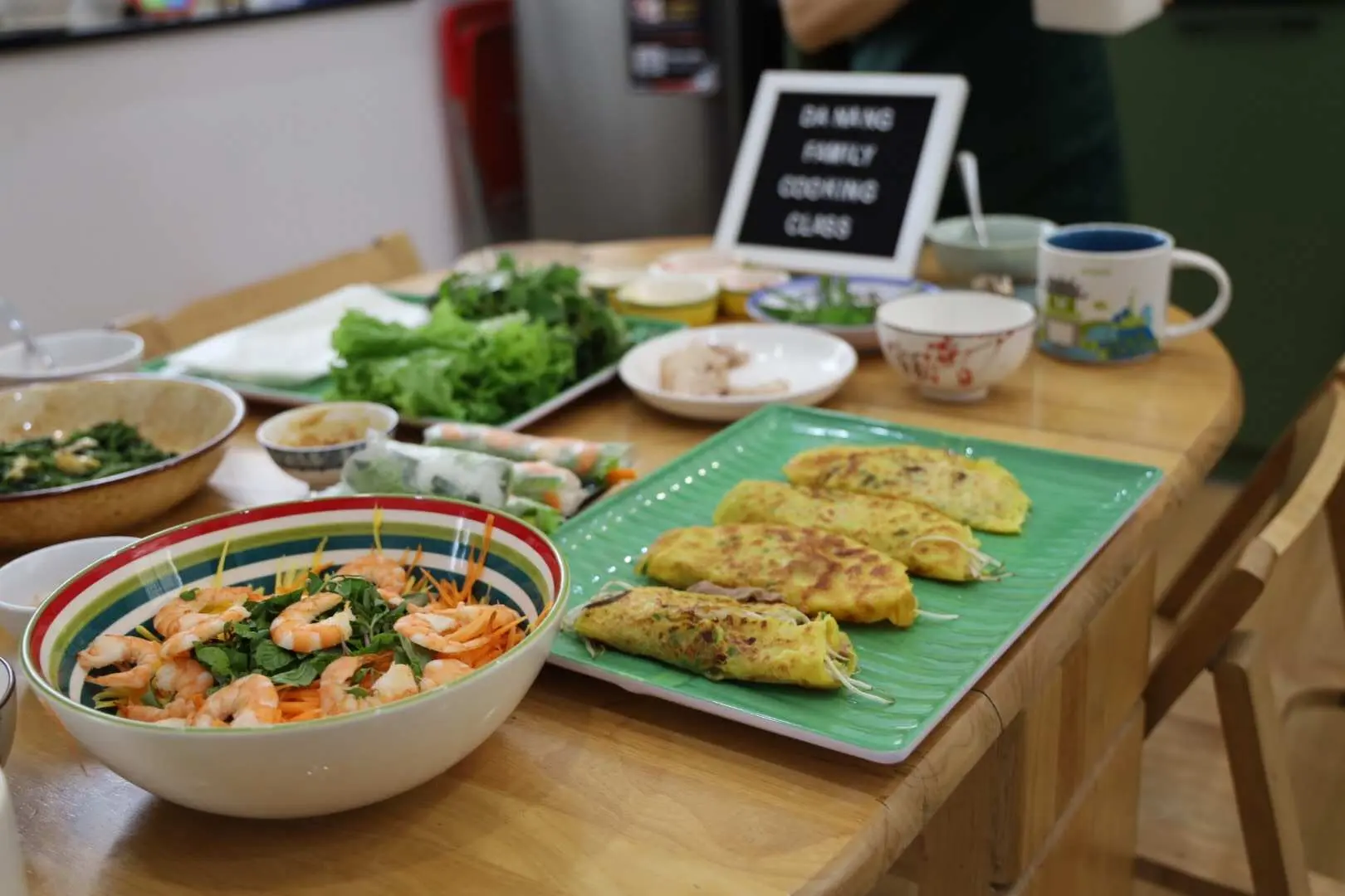 The bountiful outcome of a Da Nang family cooking class, with the table filled with various Vietnamese dishes such as shrimp salad, Banh Xeo, and spring rolls, showcasing the authentic Vietnamese creations made by participants.