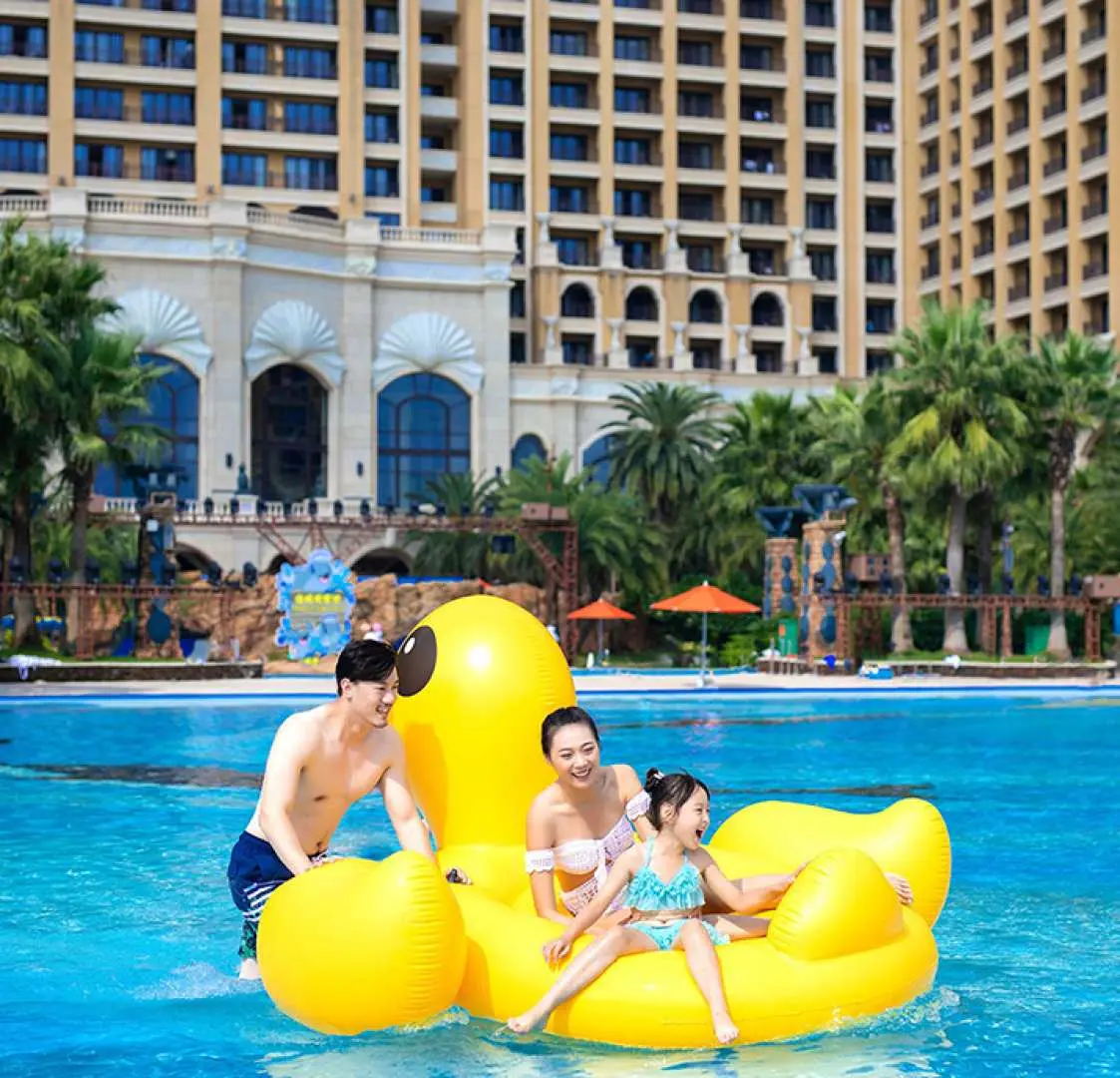 一家三口在珠海長隆橫琴灣水世界，興奮地乘坐巨型黃色小鴨造型充氣船，盡情享受泳池樂趣。