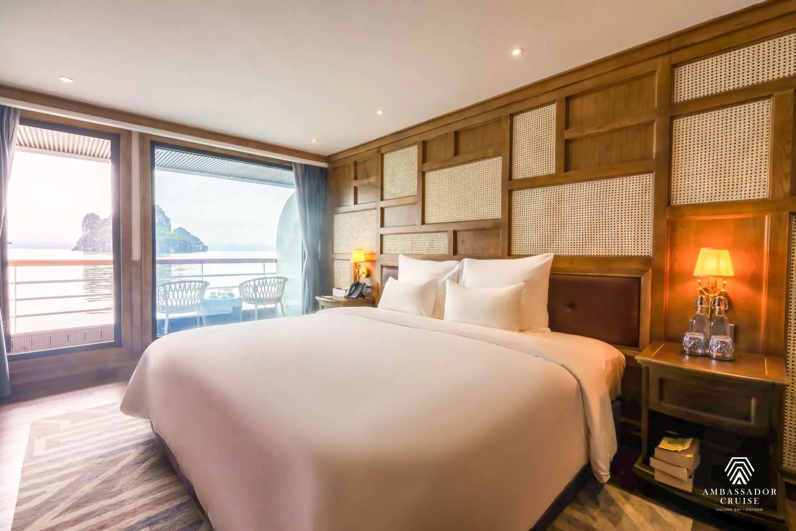 Elegant restaurant on the Ambassador luxury cruise, with attentive staff preparing tables, offering serene views of Halong Bay's waters and limestone cliffs.