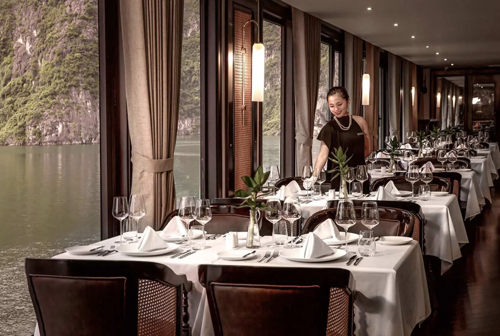 Spacious luxury cabin on the Ambassador cruise, featuring a comfortable double bed and a private balcony offering stunning sea views of Halong Bay.