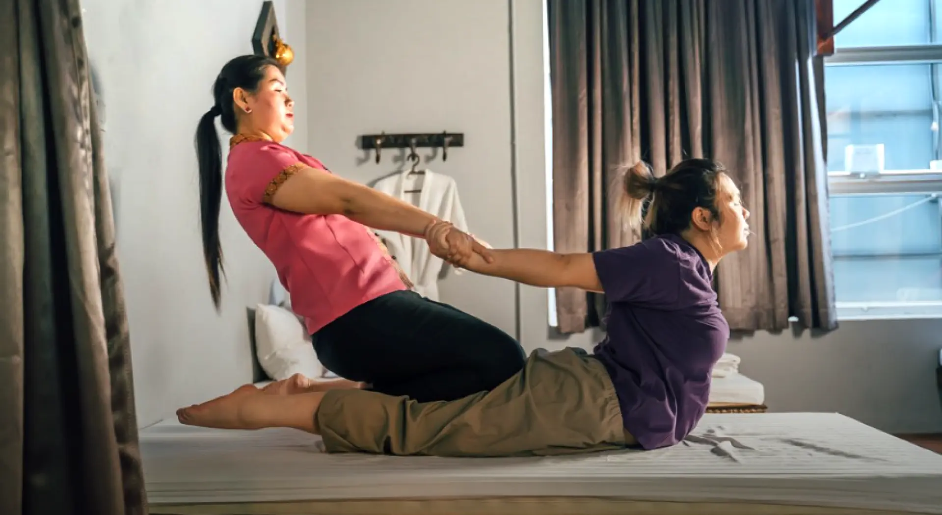 A certified therapist in Kuala Lumpur performing a traditional Thai massage with full-body stretching and soothing movements, promoting relaxation and well-being at an ancient herbal spa.